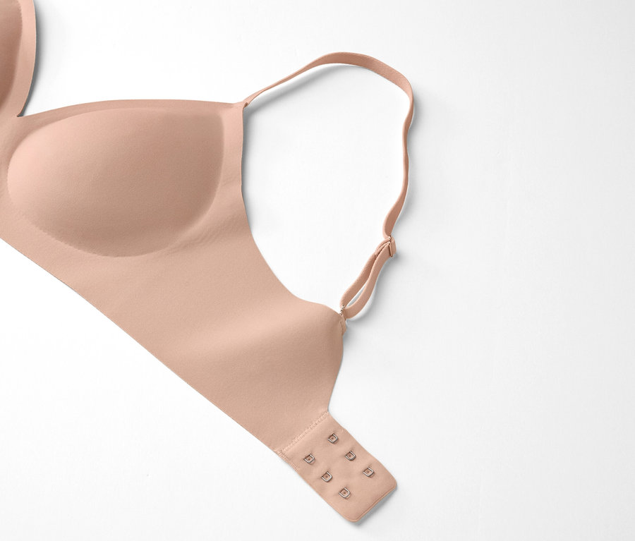 Un soutien-gorge couleur chair est posé sur un fond blanc.