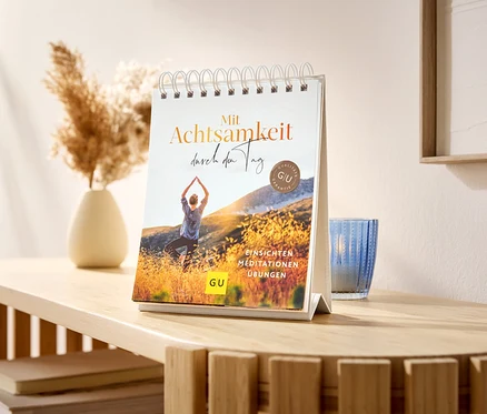 Sur une table se trouve un présentoir de table »Mit Achtsamkeit durch den Tag«.