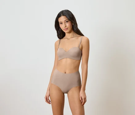 Femme portant un soutien-gorge bandeau et une culotte taille haute beige.
