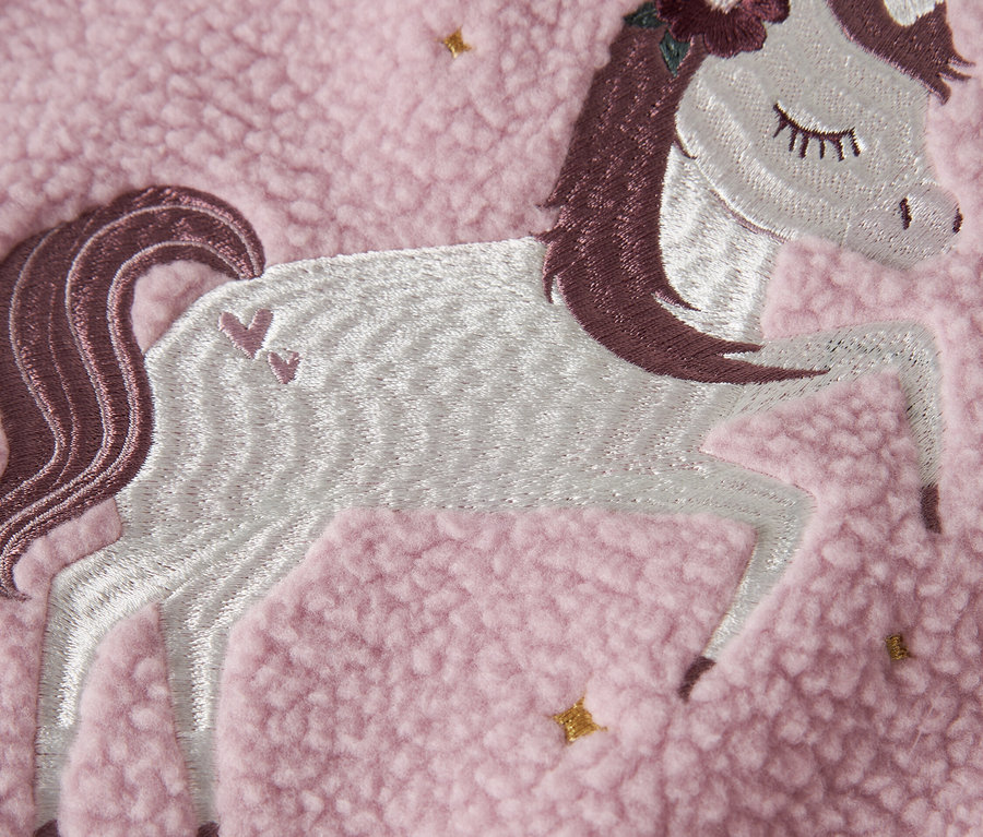 Gros plan d'un tissu polaire rose avec un appliqué de licorne brodé.
