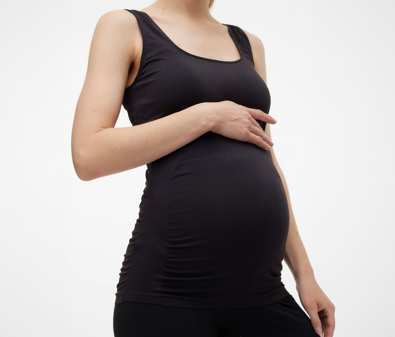 Femme enceinte portant un débardeur noir MAMALICIOUS «
MLHEAL
» taille unique, posant sa main sur son ventre.