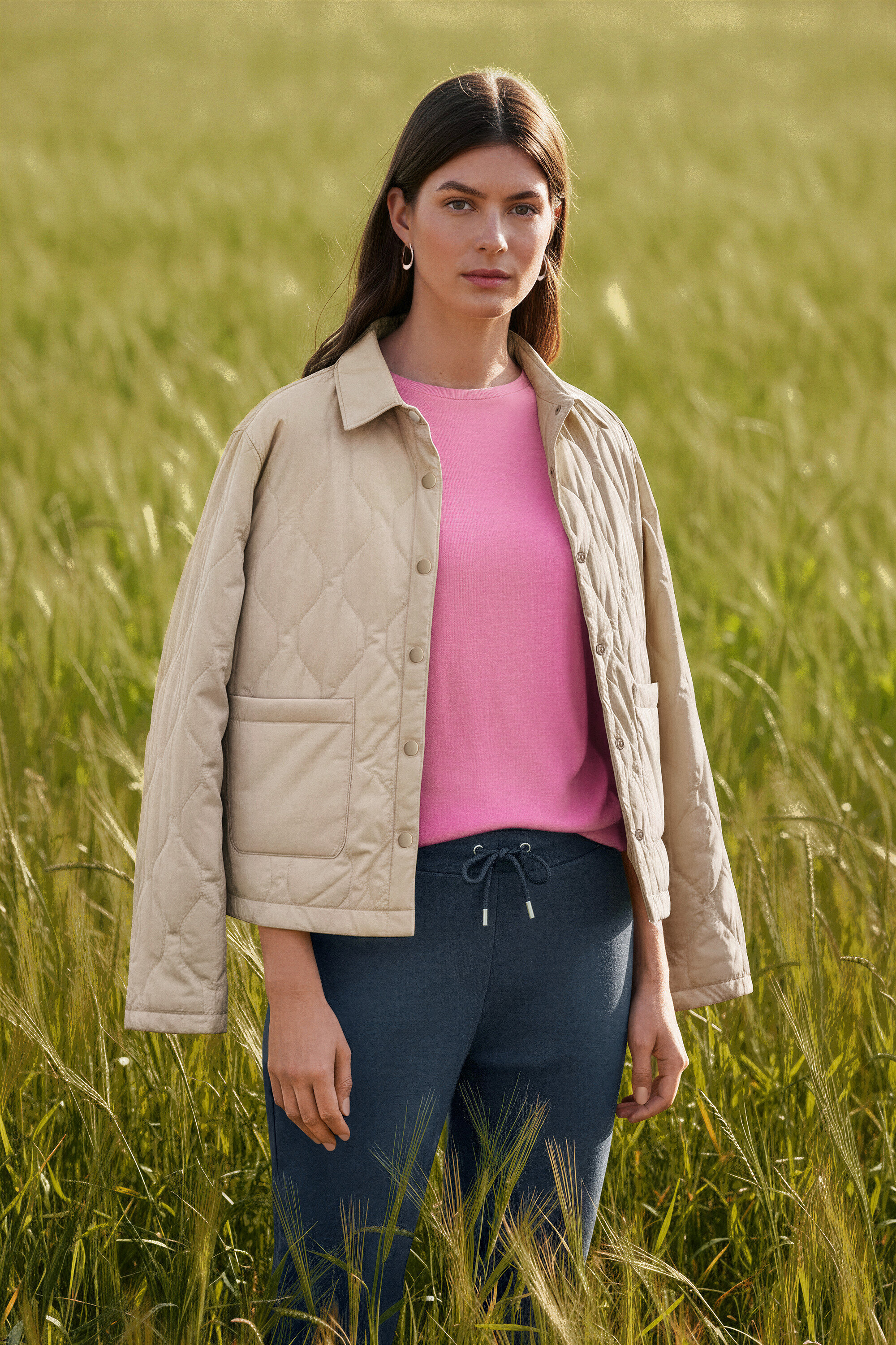 Femme debout dans un champ portant des Créoles vague.