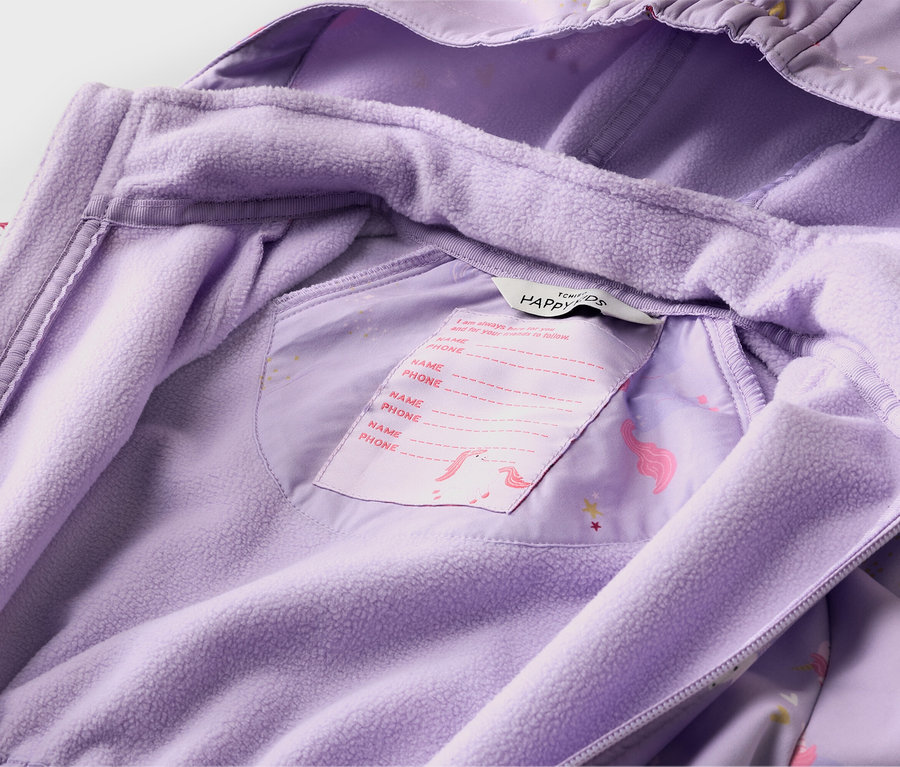 Gros plan sur la doublure intérieure d'une veste violette avec un motif de licorne et une étiquette pour écrire le nom et le numéro de téléphone.
