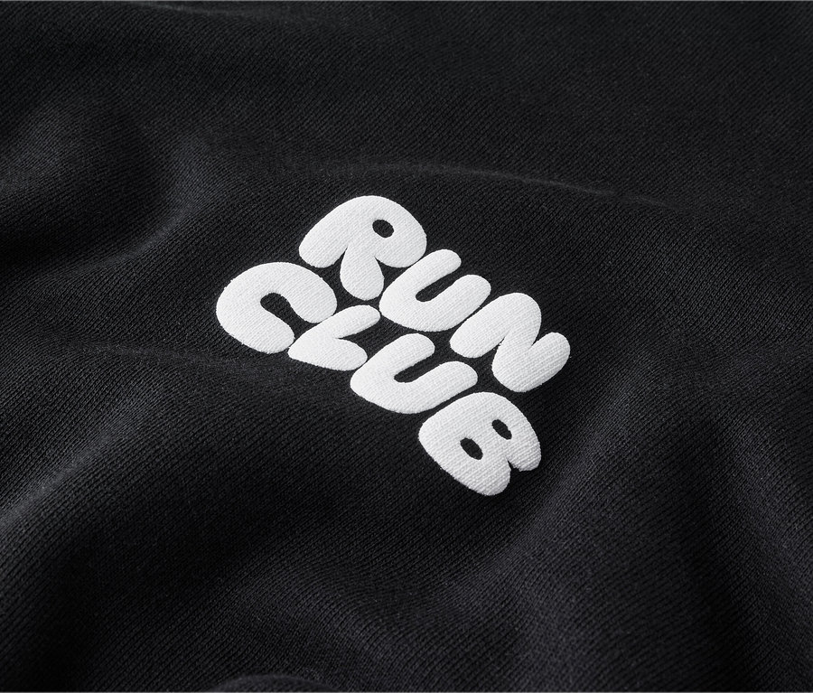 Gros plan d'un sweatshirt noir avec la broderie blanche « RUN CLUB ».
