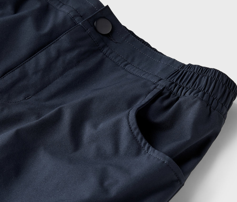 Gros plan d'un pantalon bleu marine avec un bouton et une taille élastique.