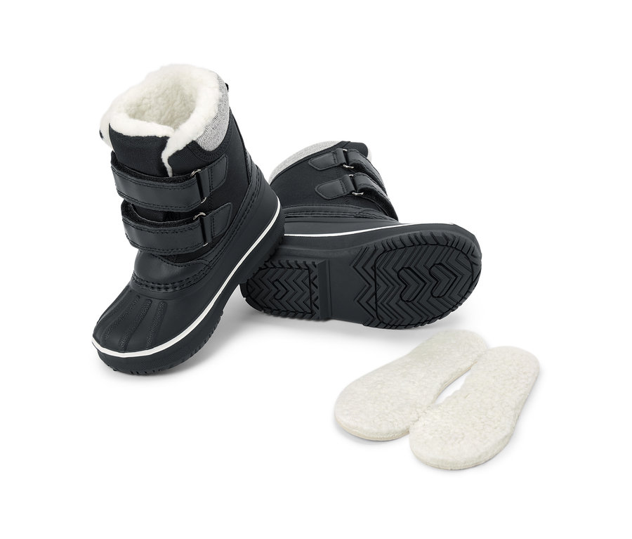Deux bottes de neige noires avec doublure en fausse fourrure blanche, trois scratchs et des semelles noires robustes avec une bande blanche. À côté se trouvent deux semelles intérieures blanches et moelleuses.