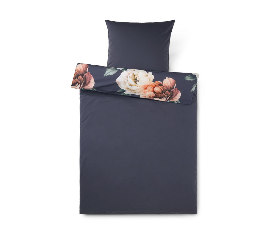 Parure de lit gris foncé avec un motif floral sur le bord supérieur replié, montrant de grandes fleurs crème et brun rougeâtre sur un fond sombre.