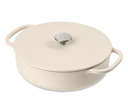 Une cocotte basse en fonte couleur crème avec couvercle et poignée argentée.