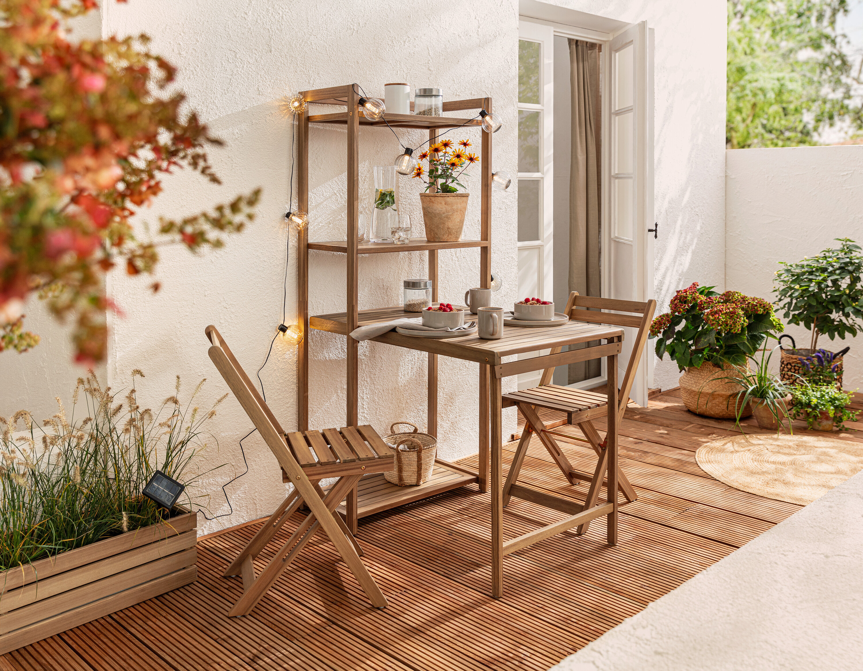 Ensemble de salle à manger de balcon »Lenja« avec étagère et guirlande lumineuse solaire, boules rainurées sur un balcon.