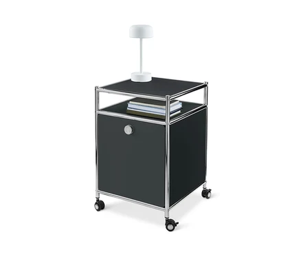 Un caisson en métal à roulettes « CN3 » avec abattant, noir, avec une lampe et des livres sur le dessus.
