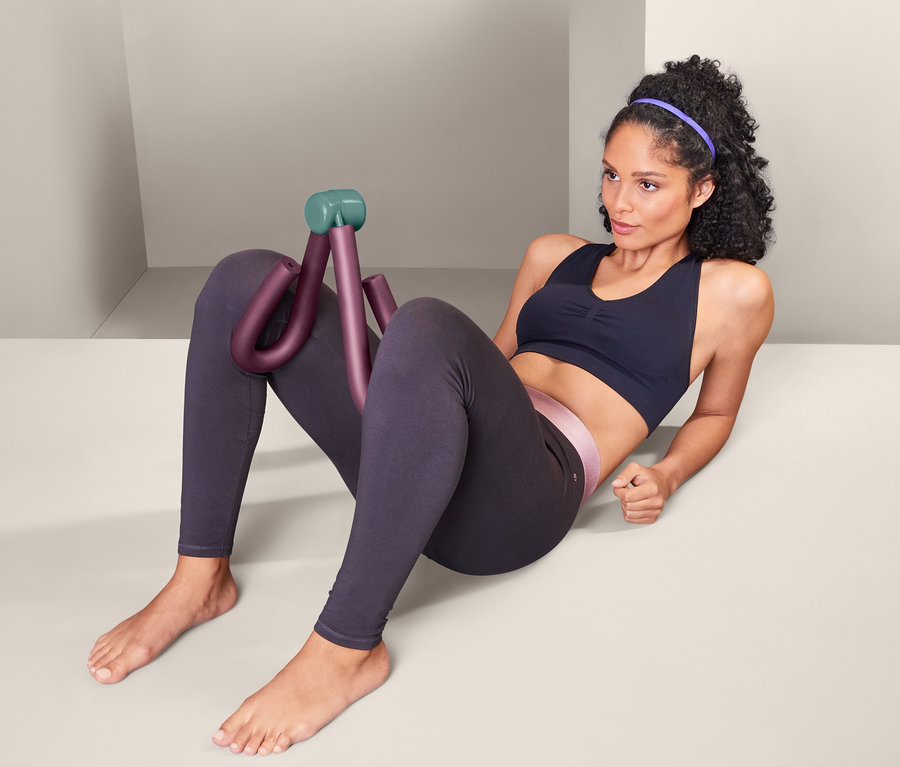 Femme assise utilisant un appareil de musculation pour bras et jambes.