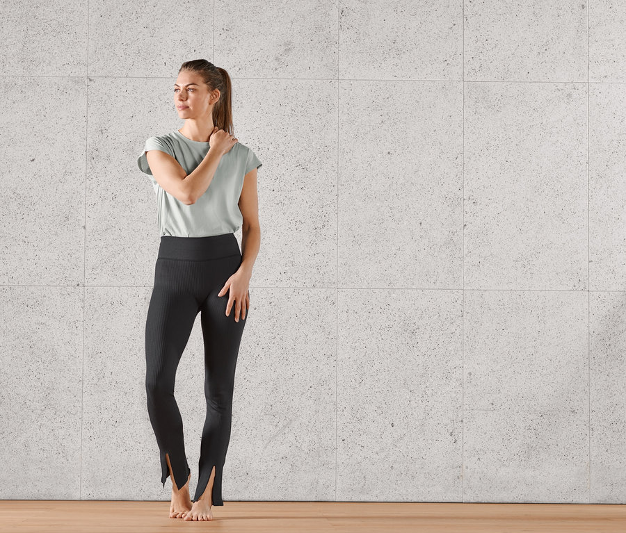 Femme posant en pantalon de sport évasé noir sans coutures, avec fente.