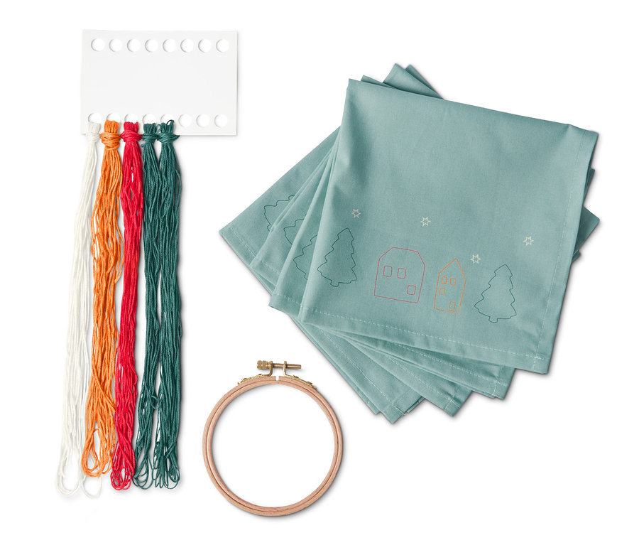 Kit pour broder 4 serviettes, avec des fils colorés et un cadre en bois.