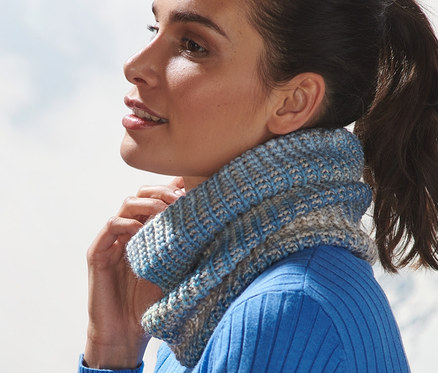 Femme avec un pull et une écharpe tube en maille regardant dehors.