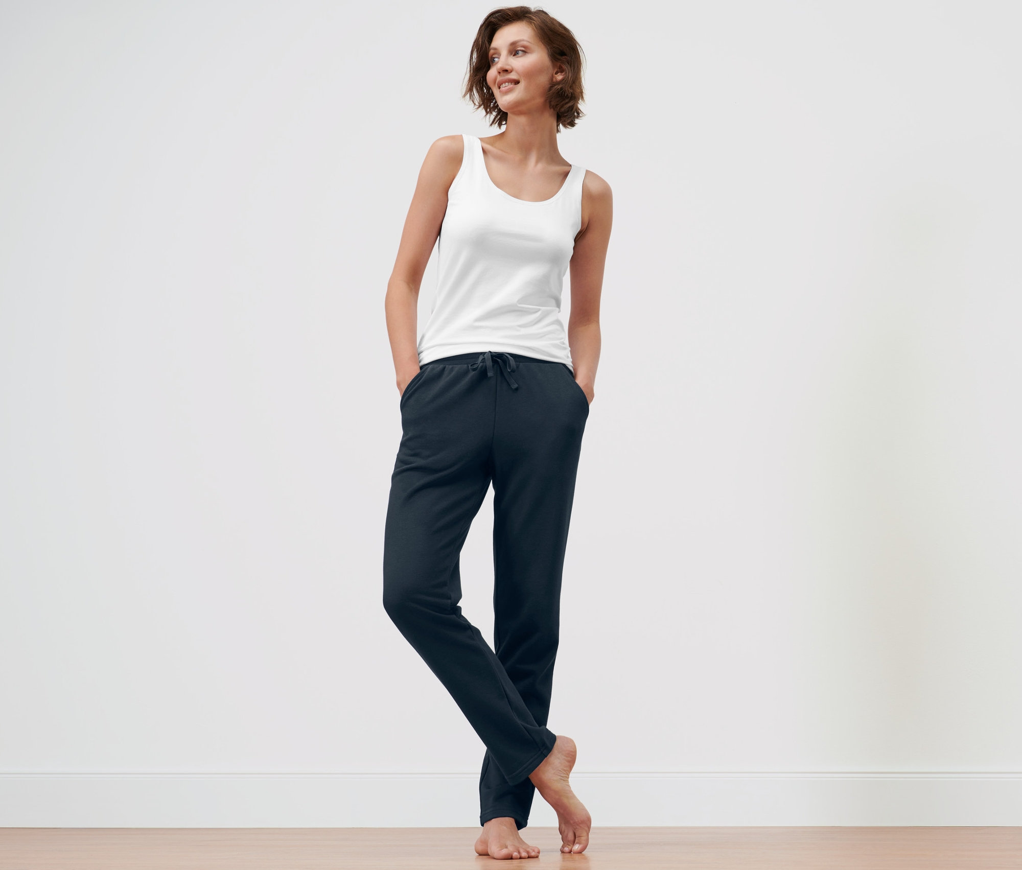 Femme debout avec les mains dans les poches d'un pantalon d’intérieur bleu foncé et d'un pantalon d’intérieur bleu.