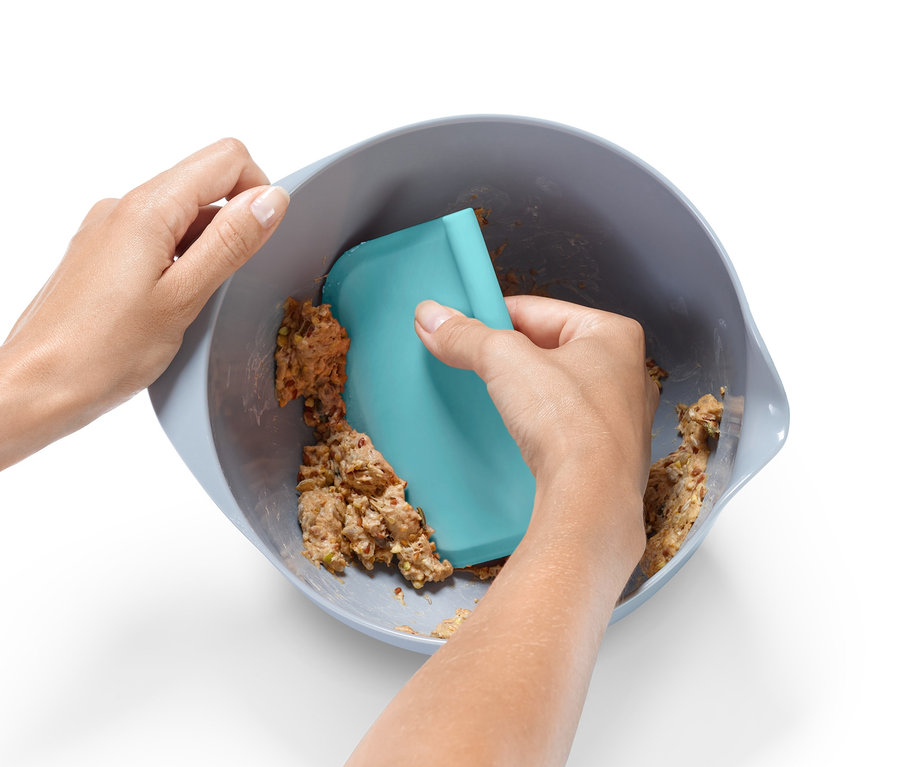 Mélange manuel de pâte dans un bol avec une spatule bleue d'un lot d'ustensiles de pâtisserie.