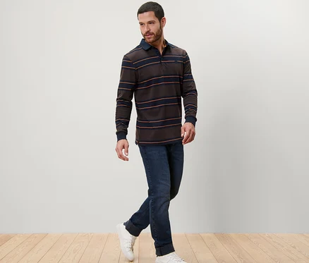 Un homme marche et porte un polo à manches longues, un jean et des baskets.
