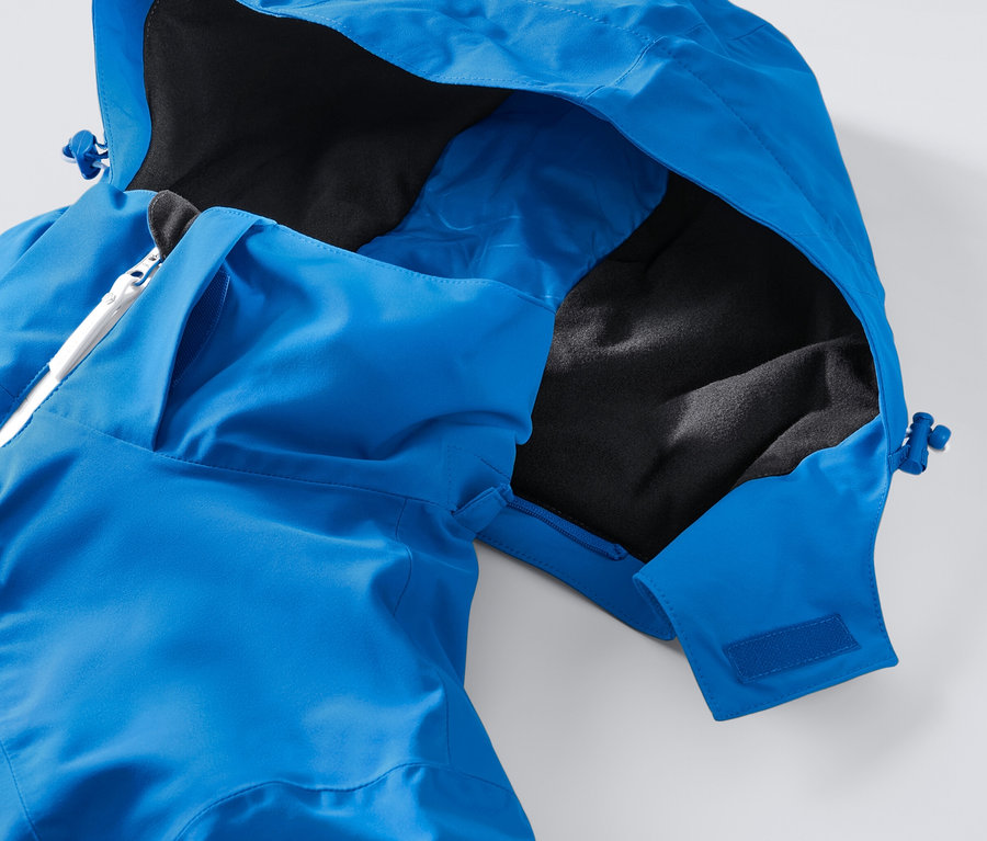 Gros plan sur une veste de ski high-tech bleue avec capuche et fermeture éclair blanche.