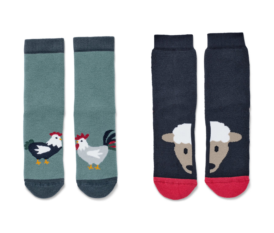 Deux paires de chaussettes antidérapantes pour tout-petit sur le thème de la ferme. Une paire est verte avec des coqs, l'autre bleu foncé avec des moutons.