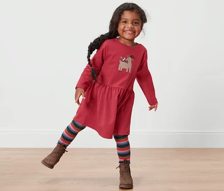 Petite fille souriante posant dans une robe sweat rouge pour tout-petits.