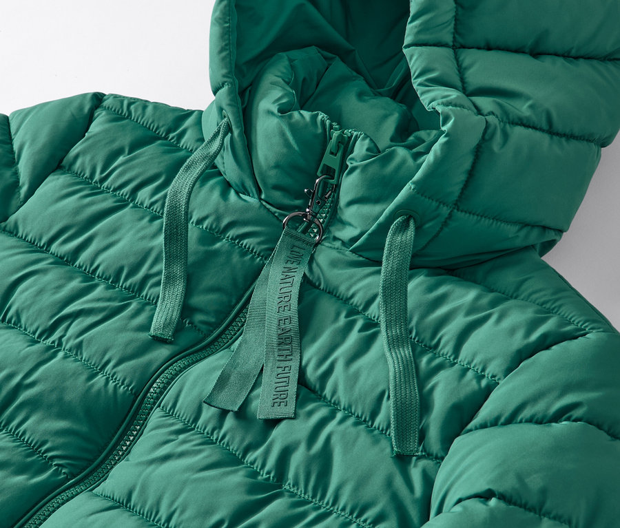 Gros plan sur un manteau matelassé à capuche vert.