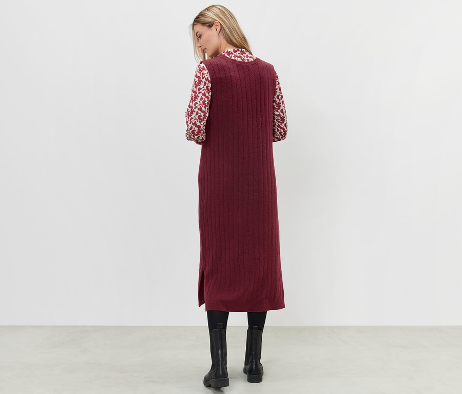 Une femme se tient dos à la caméra et porte une robe en tricot côtelée rouge.