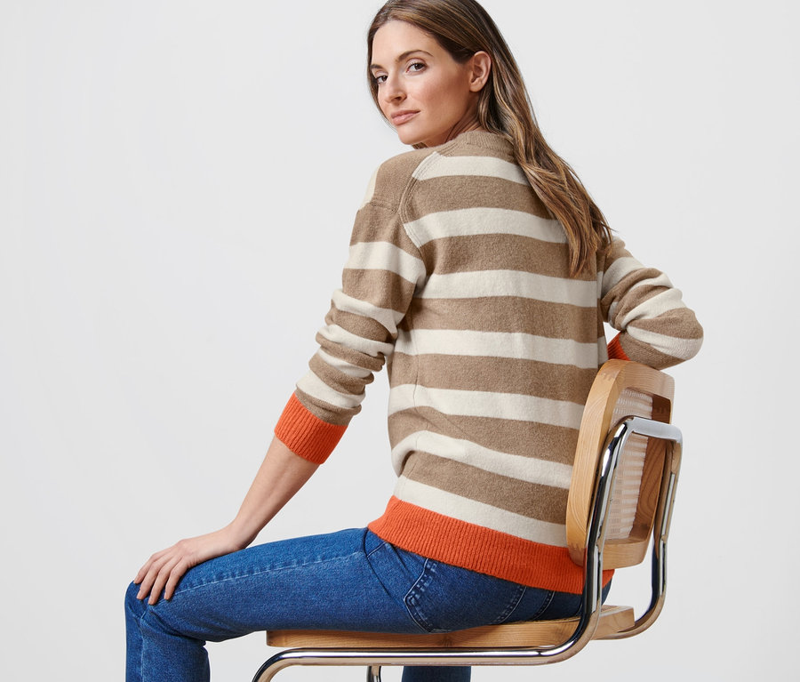 Femme assise sur une chaise portant un pull en maille à rayures.