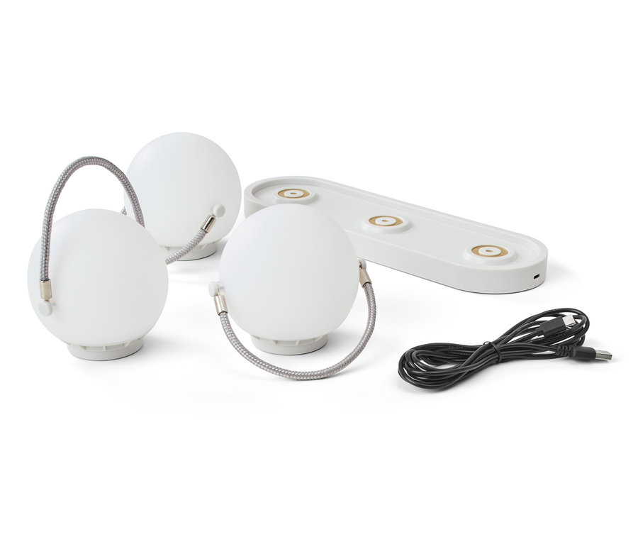 Trois lampes de table à batterie, une station de charge et un câble sur fond blanc.