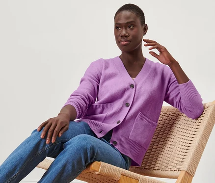 Femme assise dans un fauteuil portant une jaquette en maille.