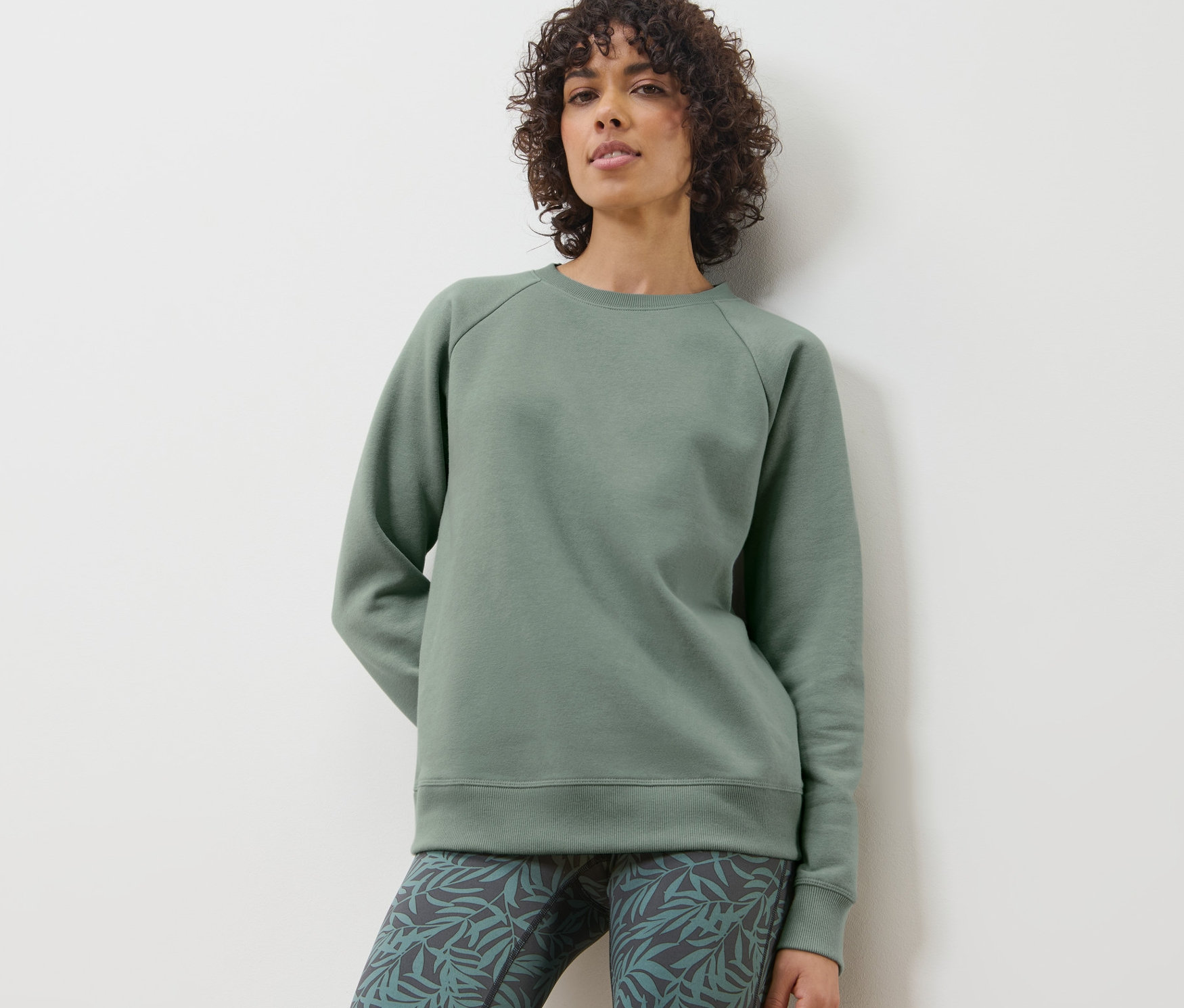 Femme posant en sweatshirt de yoga et leggings à motif de feuilles.