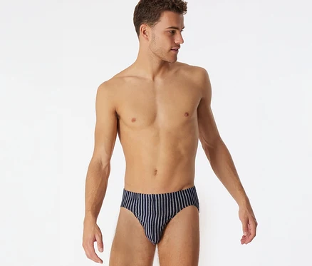 Homme torse nu, regardant à droite, portant un slip Supermini SCHIESSER bleu foncé à rayures.