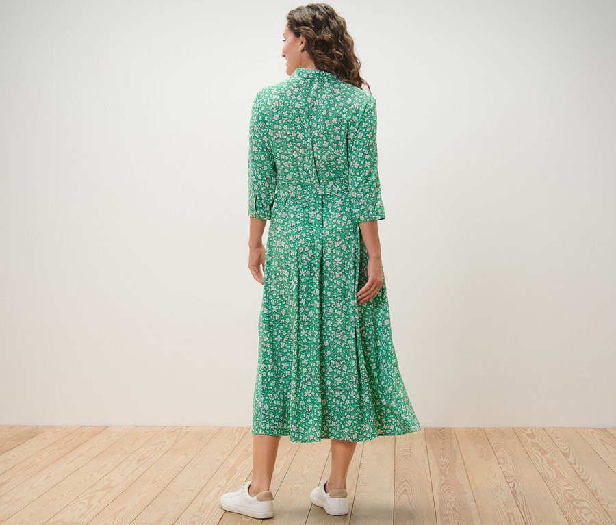 Femme vue de dos portant une robe chemise imprimée verte.