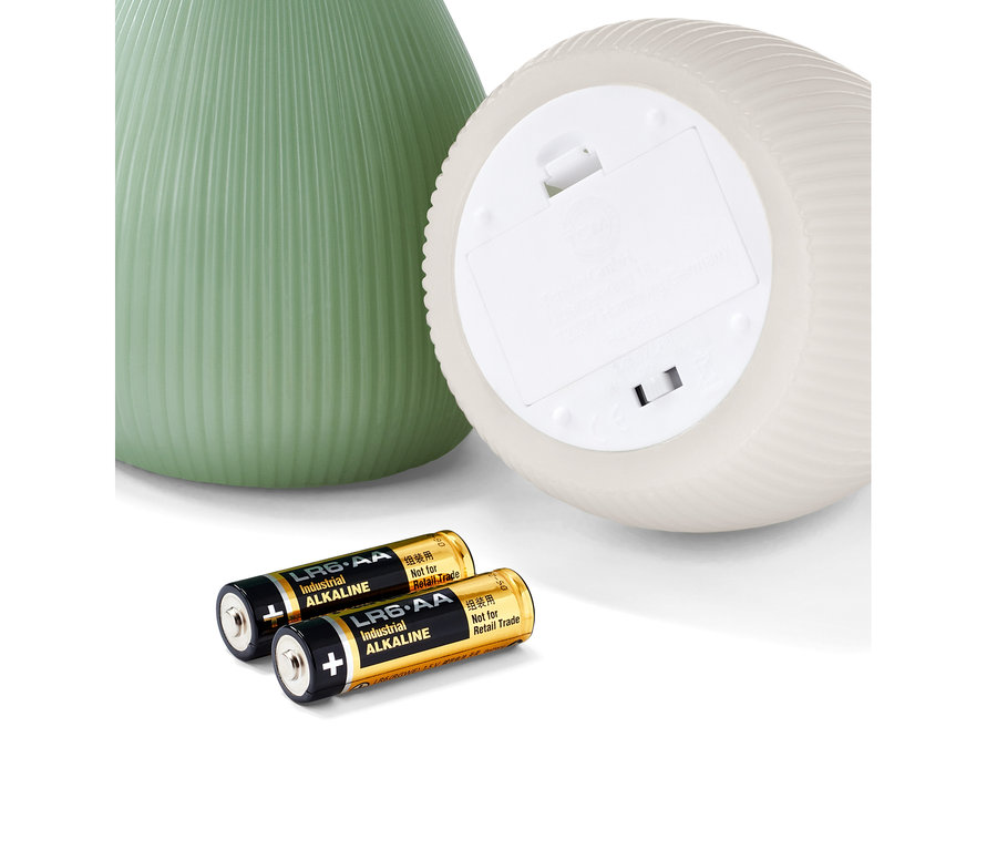 Deux bougies à LED en cire véritable, une verte et une blanche, sont posées à côté de deux piles.