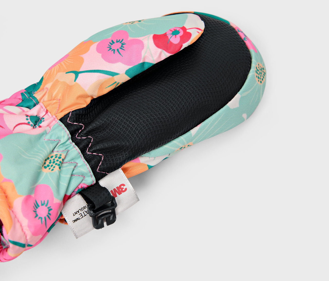 Gros plan d'une moufle fleurie multicolore avec doublure intérieure noire et une sangle réglable.