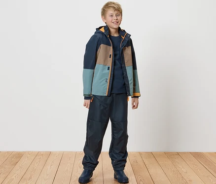 Un garçon debout portant un pantalon softshell pour enfants.