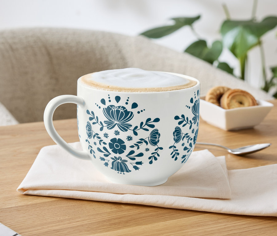 Une tasse de café avec un motif floral bleu sur une serviette.