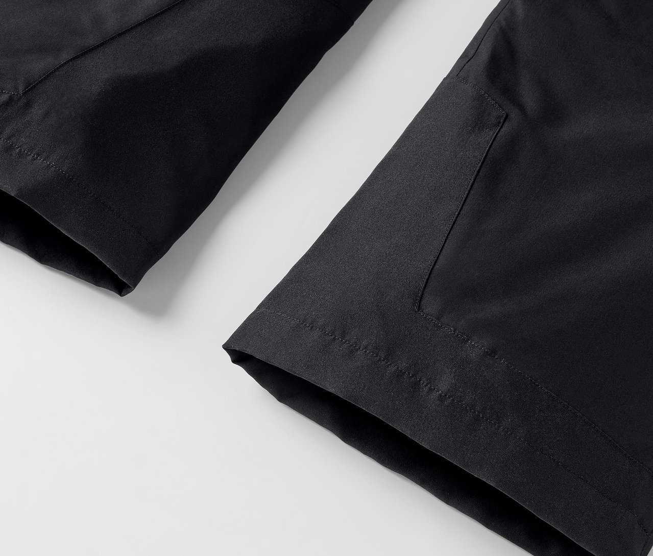 Gros plan d'un pantalon noir avec une poche sur un fond blanc.