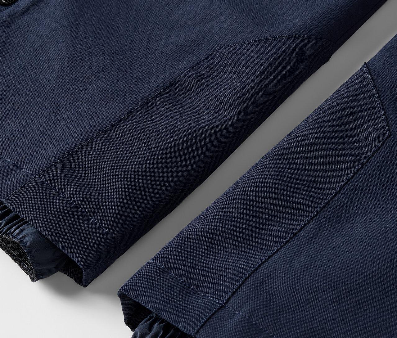 Gros plan sur deux jambes de pantalon bleu marine avec des ourlets élastiqués.