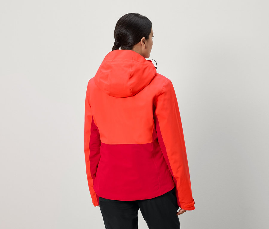 Une femme, vue de dos, porte une veste rouge-orange à capuche.
