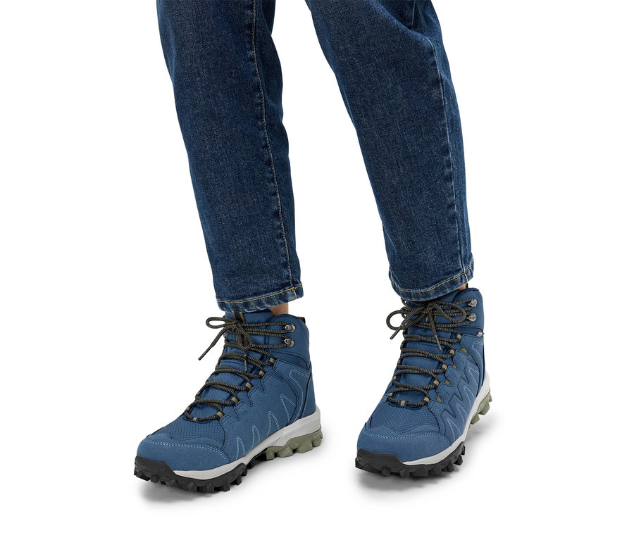 Personne portant des chaussures de randonnée bleues et un jean.