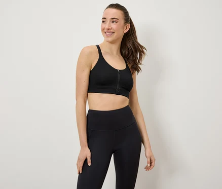 Une femme porte un soutien-gorge de sport et des leggings noirs.