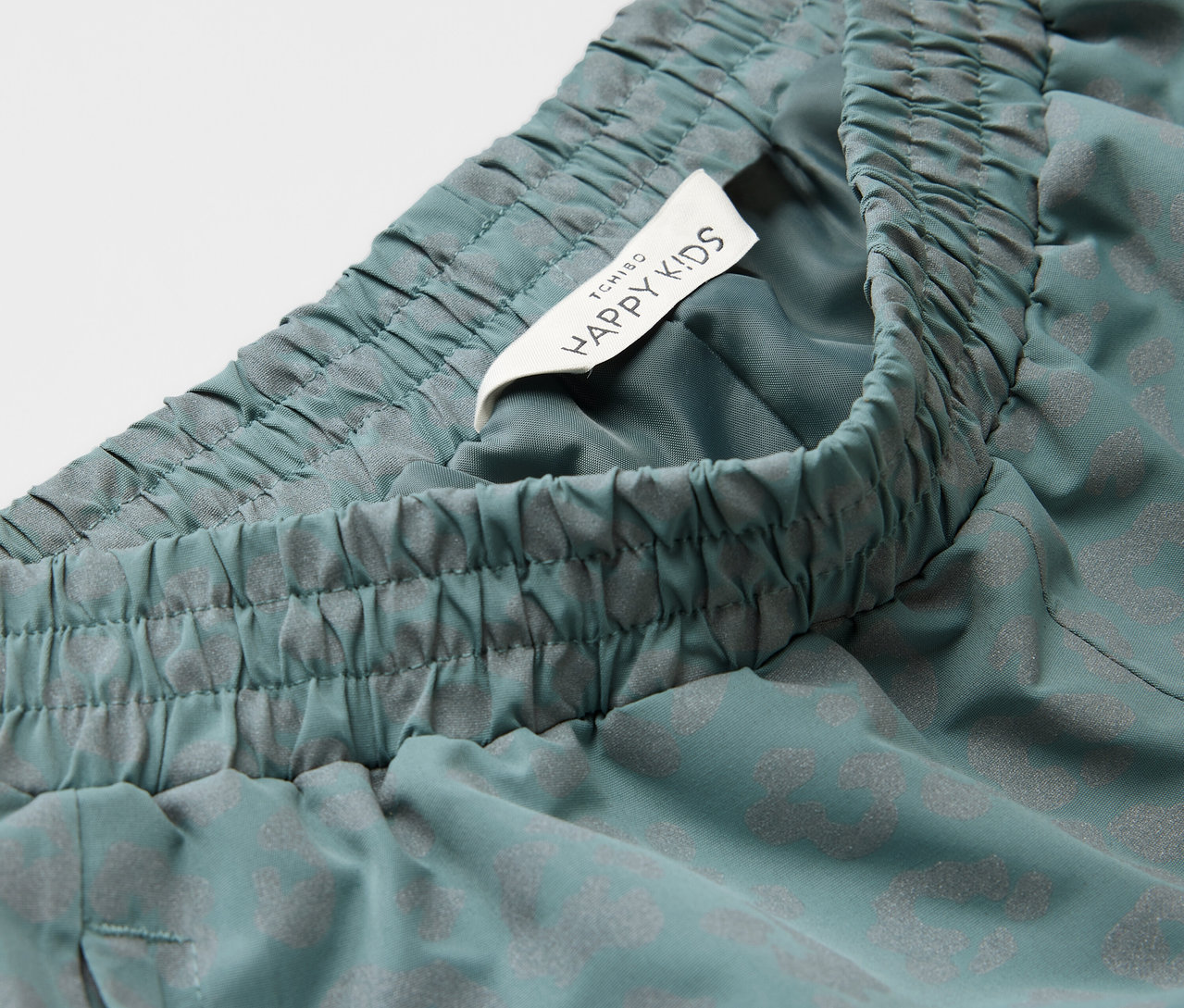 Détail d'un pantalon de pluie pour enfant avec des éléments réfléchissants.