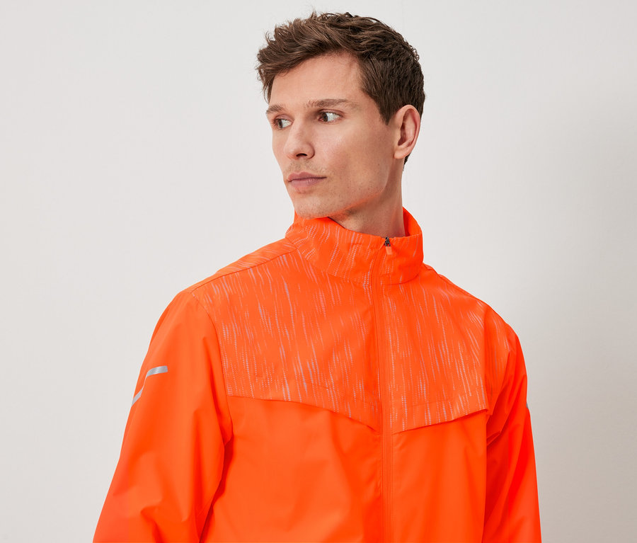 Un homme aux cheveux bruns porte une veste orange.