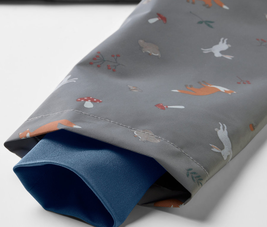 Détail d'une veste de pluie thermique pour enfant avec renards, lièvres et champignons.