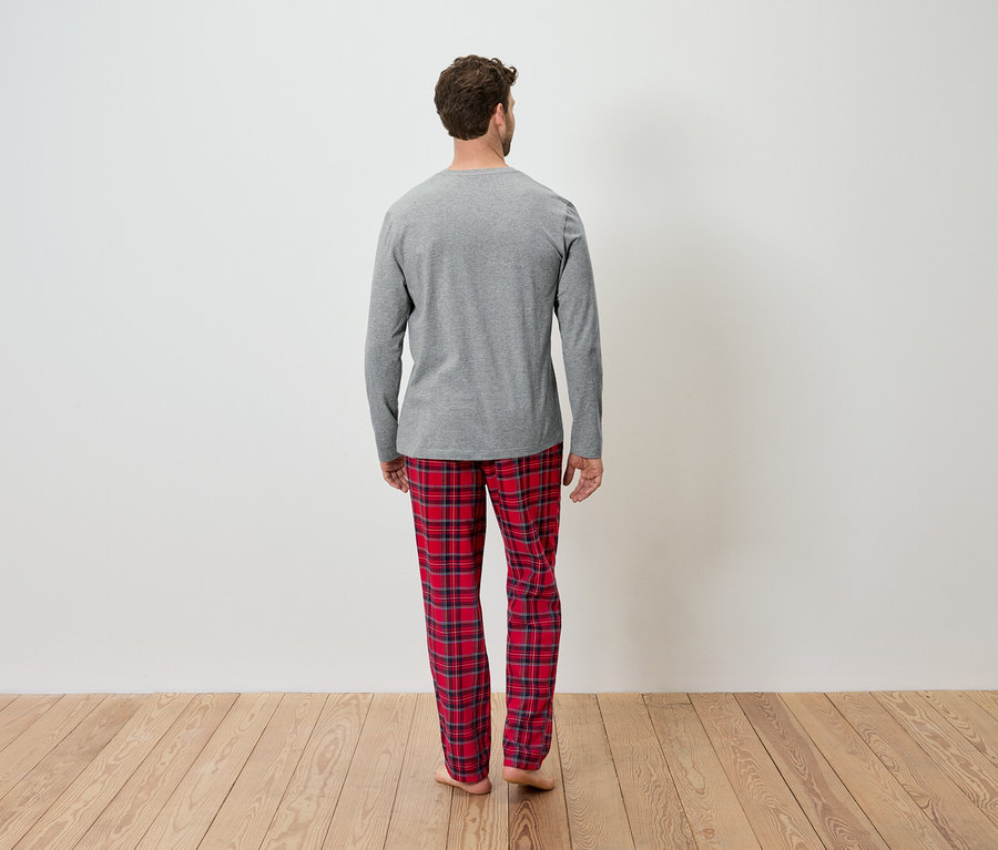 Un homme vu de dos porte un t-shirt gris à manches longues et un pantalon rouge à carreaux.