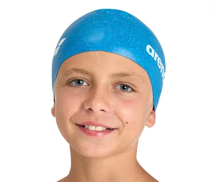 Un garçon souriant porte un bonnet de bain arena Junior en silicone bleu pour enfant.