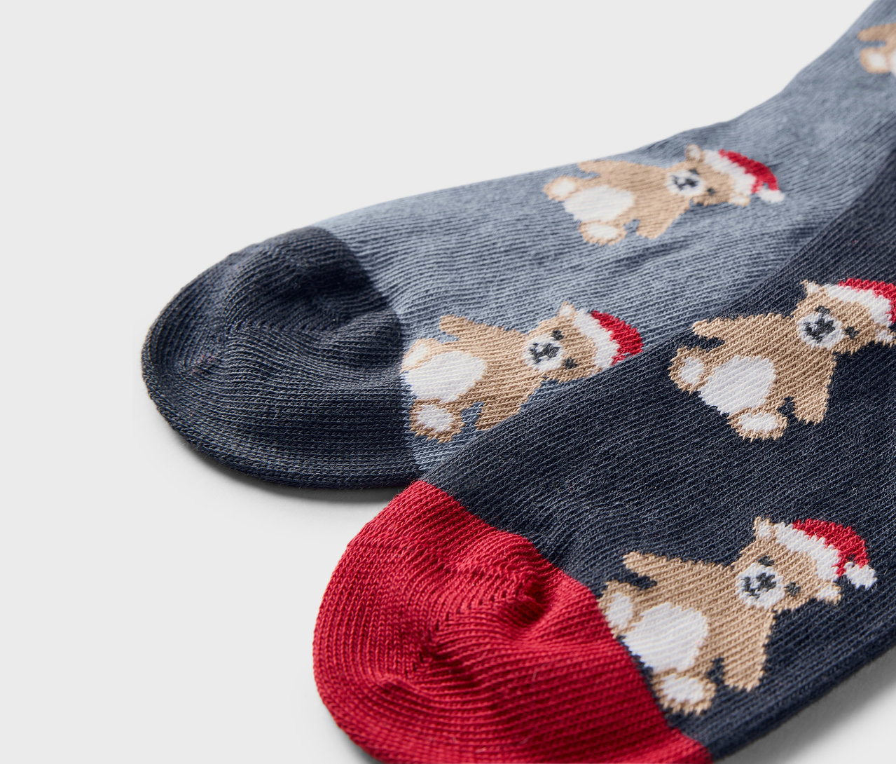 Gros plan de deux paires de chaussettes de Noël avec des ours portant des bonnets.