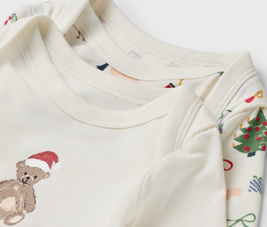Deux cache-couches blancs à manches longues pour bébé avec des motifs de Noël.