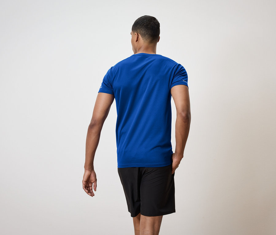 Un homme vu de dos porte un t-shirt bleu et un short noir.