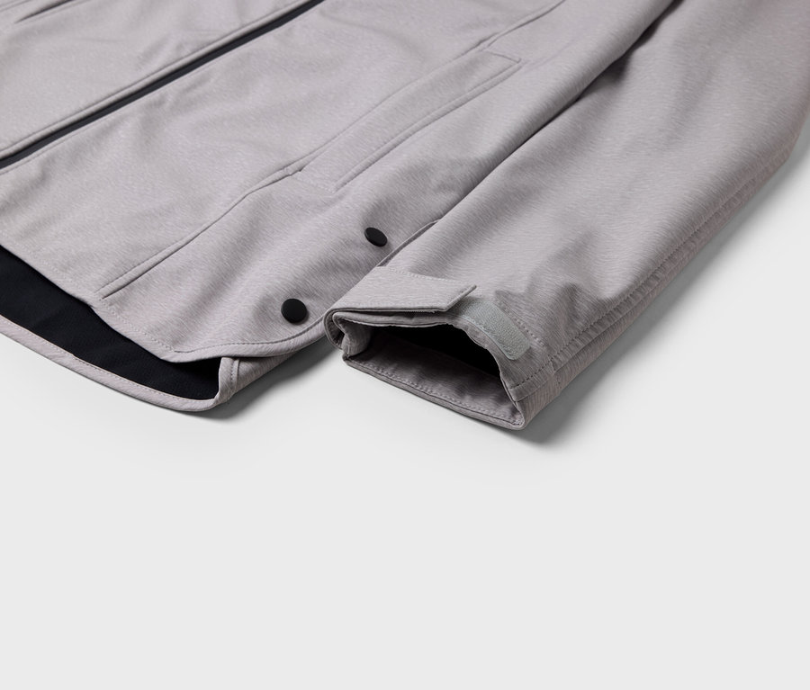 Détail d'une veste grise avec une bordure noire et une fermeture à boutons-pression.
